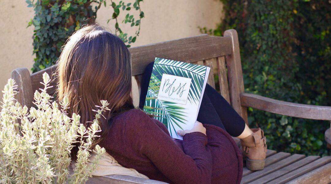 Introducing Bless - A young woman reclining outdoors looking at a Bless Women's Bible Study workbook